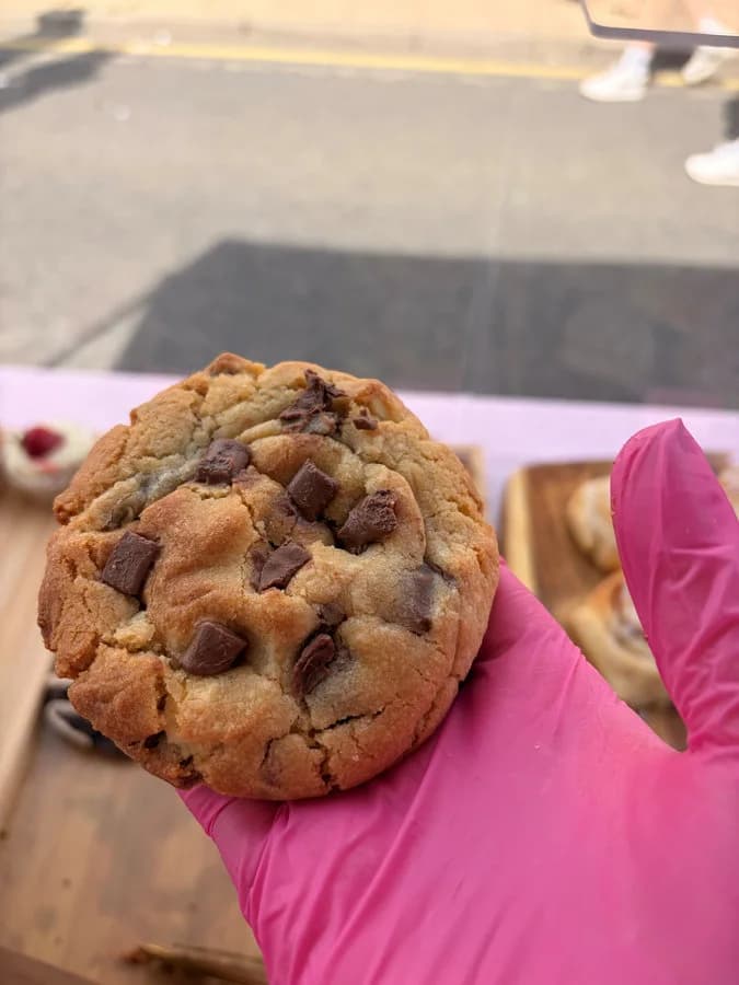 A thick chocolate chip cookie held up at the market